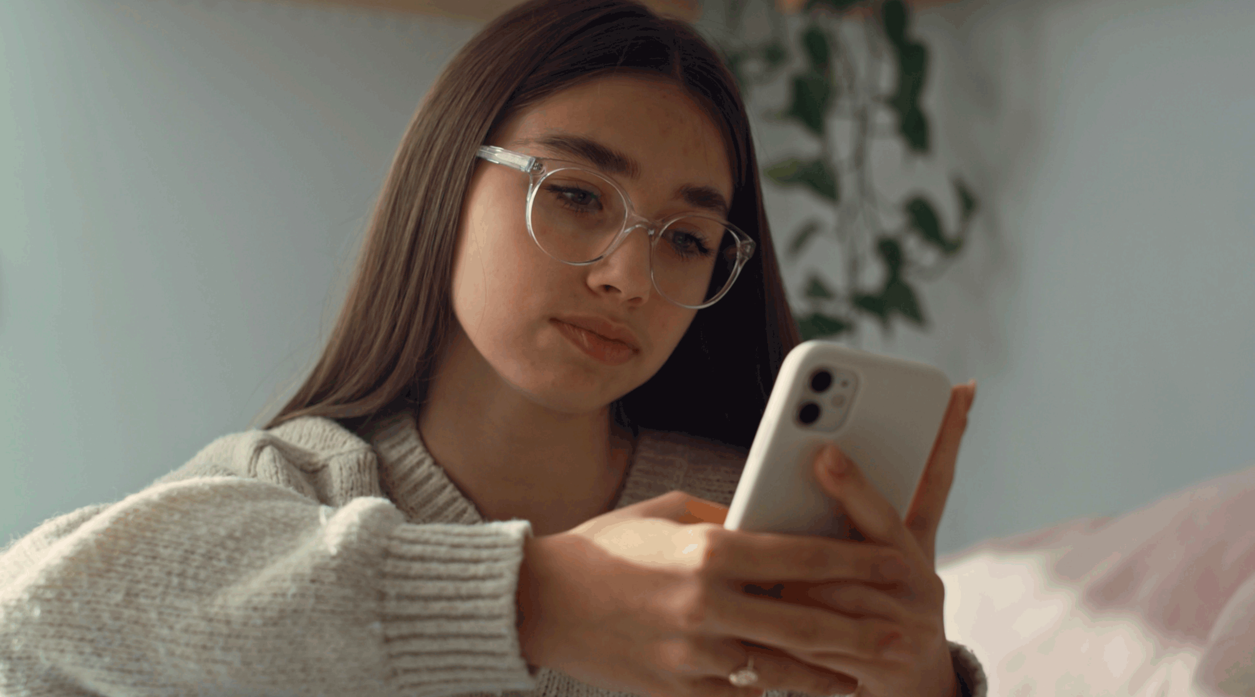 Close up of caucasian teenage girl browsing phone in her bedroom